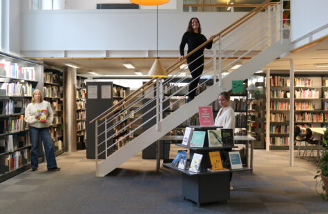 Tre kvinner står inne i et bibliotek.