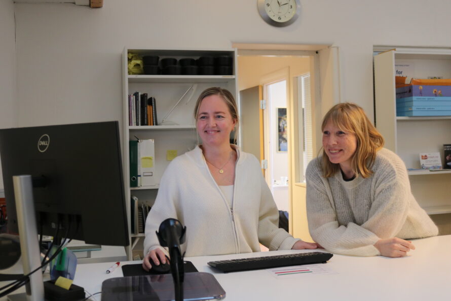 To kvinner står foran en pc-skjerm.