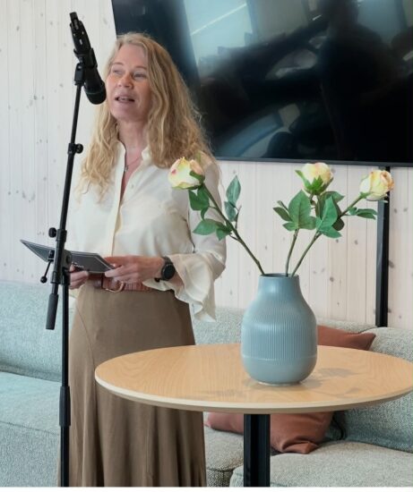 En kvinne i skjørt snakker i en mikrofon.