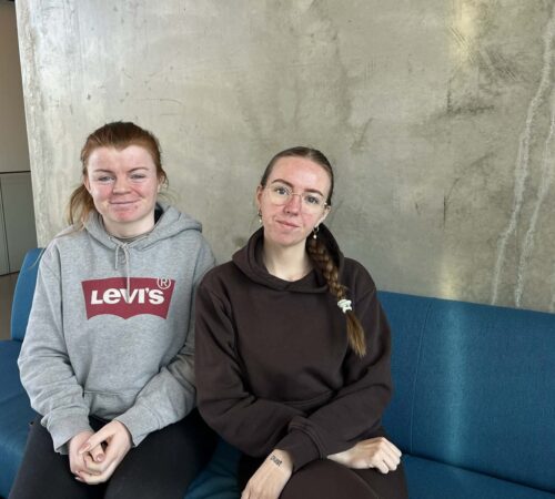 To unge kvinner sitter i en blå sofa.