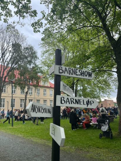Et skilt som peker i mange retninger. der det blant annet står barneshow og barneløp.