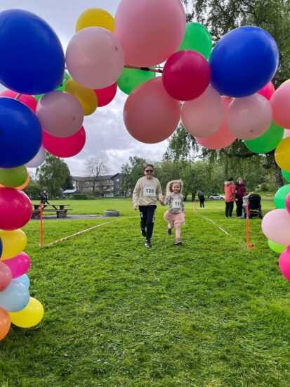 To barn løper mot en ballonbue