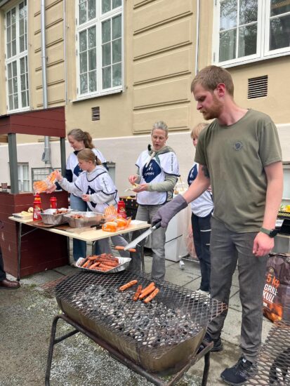 En mann griller pølser.
