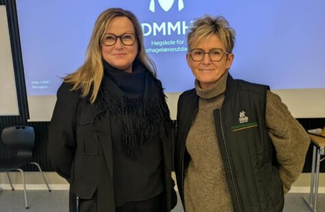 To kvinner fotografert foran DMMHs logo.