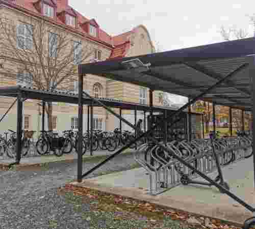 Bilde av sykkelparkeringen fra utsiden. I bakgrunnen ser vi hovedbygget.