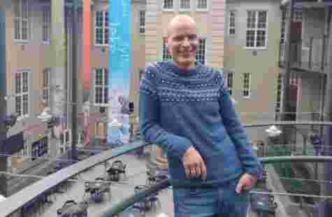 Høgskolelektor Tormod Murud-Riser lener som mot et gelender og smiler i Glassgården.