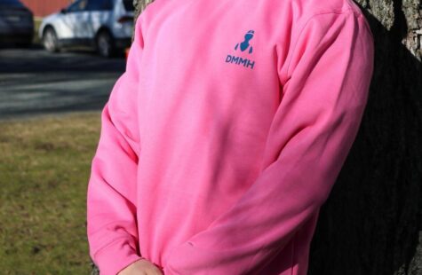 College genser, rosa Mannlig student lener seg mot et tre i en rosa DMMH college geneser