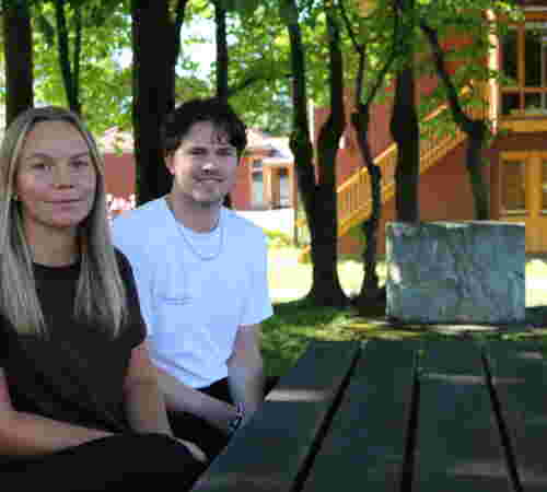 En ung mann og en ung kvinne sitter på en benk.