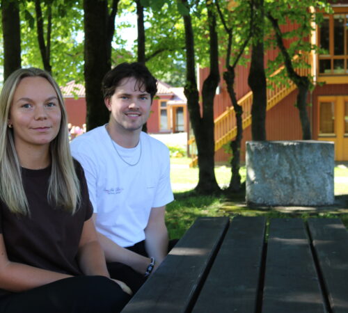 En ung mann og en ung kvinne sitter på en benk.