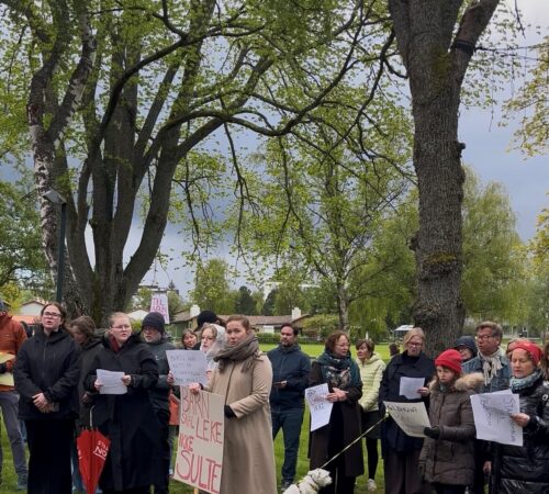 Mennesker står utendørs med plakater i hendene