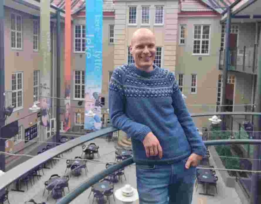 Høgskolelektor Tormod Murud-Riser lener som mot et gelender og smiler i Glassgården.