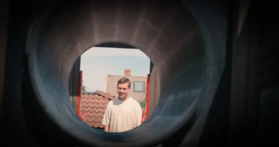 Barnehageansatt ser gjennom et leike stativ og smiler