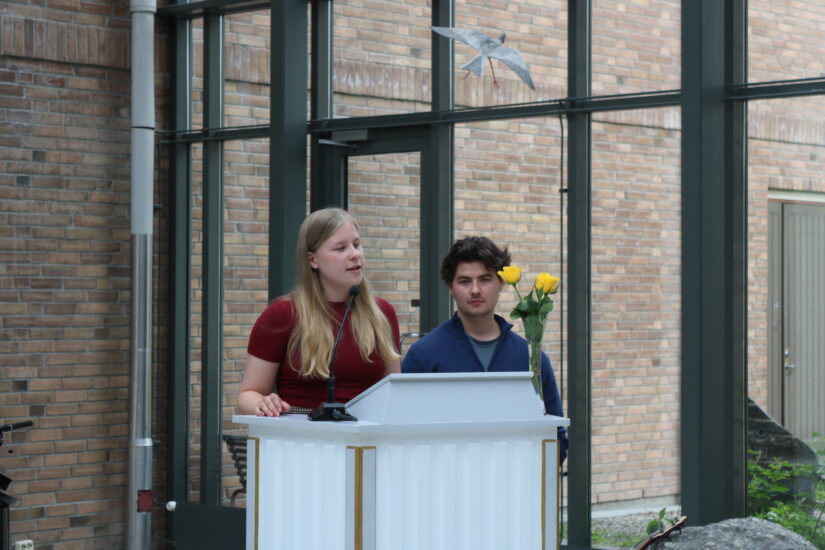 En ung kvinne og ung mann står ved en talerstol.
