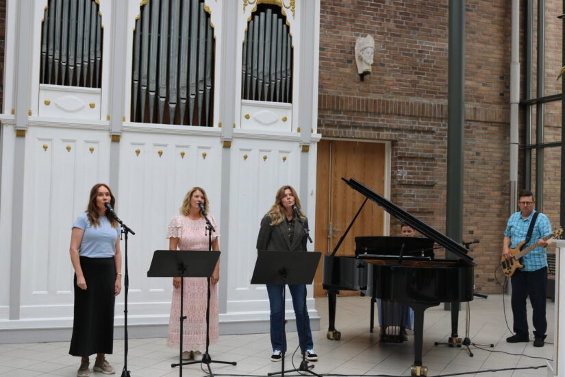 Et band på 5 medlemmer synger spiller klaver og gitar.