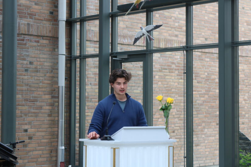 En ung mann står bak en talerstol.