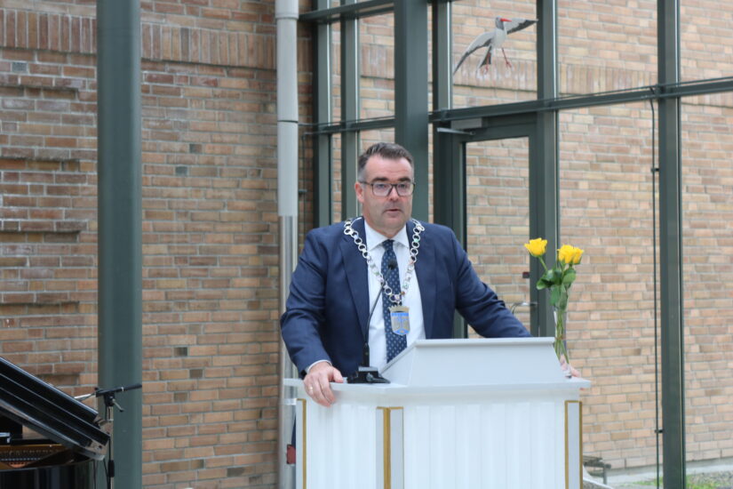 En mann med ordførerkjede står ved en talerstol.