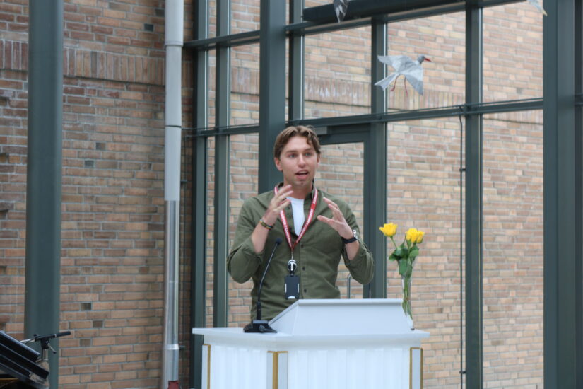 En ung mann snakker engasjert ved en talerstol.