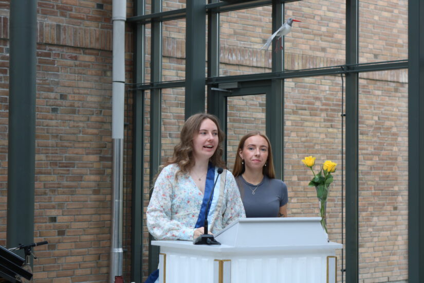 To unge kvinner står ved en talerstol.