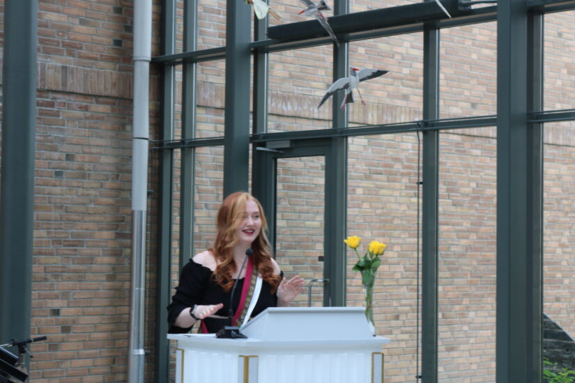 En ung kvinne står engasjert på en talerstol.