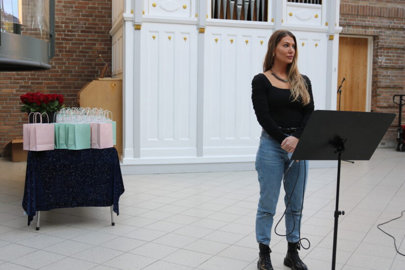 En kvinne står foran et orgel.