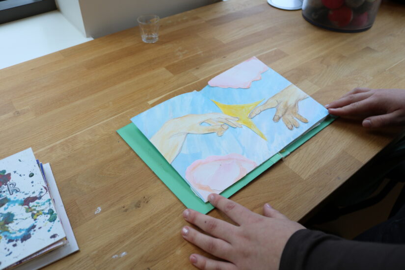 En tegnet scene med to åpne hender som når hverandre, en blå himmel, rosa skyer og en gul stjerne i midten.